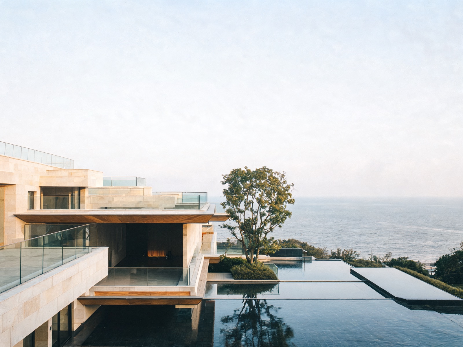 A limestone villa behind a still reflecting pool